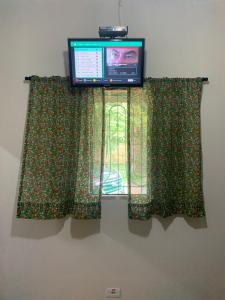 TV en la parte superior de una ventana con cortina en Casa para temporada em Peruíbe, en Peruíbe