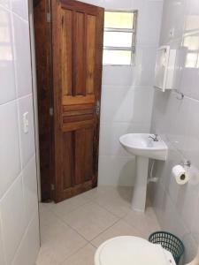 Un baño con inodoro, lavabo y puerta. en Casa para temporada em Peruíbe, en Peruíbe