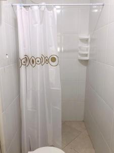 Un baño con una cortina de ducha blanca y un inodoro. en Casa para temporada em Peruíbe, en Peruíbe