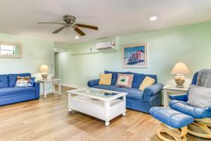 a living room with blue couches and a ceiling fan at Walk to Shore Atlantic Beach Condo with Pool Access in Atlantic Beach
