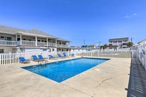 a swimming pool with blue chairs and a fence at Walk to Shore Atlantic Beach Condo with Pool Access in Atlantic Beach