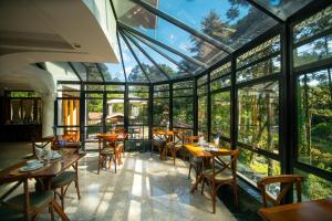 a restaurant with large windows and wooden tables and chairs at Araucária Lodge - 800 metros do Capivari in Campos do Jordão