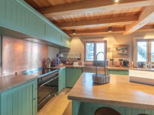 a large kitchen with green cabinets and wooden ceilings at Chalet aux pieds des pistes avec spa, sauna et parking - FR-1-645-43 in LʼHuez