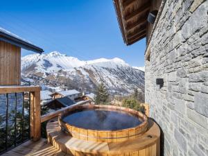 a hot tub on a deck with mountains in the background at Chalet spacieux avec bain nordique, hammam et vue proche des pistes - FR-1-570-66 in Saint-Martin-de-Belleville