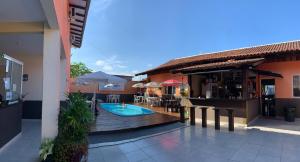 an outdoor patio with a swimming pool and a bar at Pousada Fênix,com piscina -250 METROS DA PRAIA in Pontal do Paraná