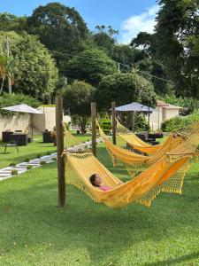 a woman laying in a hammock in a park at Pousada Flores do Campo in Águas de Lindoia