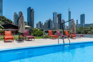 a pool with chairs and umbrellas and a city skyline at Rizzu Marina Hotel in Balneário Camboriú