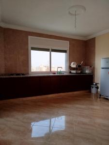 an empty kitchen with a refrigerator and a window at Résidence Nydia in Ras El Ma