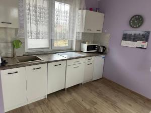 kuchnia z białymi szafkami, zlewem i kuchenką mikrofalową w obiekcie Urokliwe zacisze w Opawie w mieście Lubawka