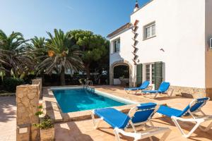 a villa with a swimming pool and chairs and a house at Villa Carmen in Es Mercadal