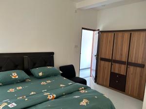 a bedroom with a green bed and a wooden cabinet at Kurulu Villa Hikkaduwa in Gonapinuwala West +30 photos