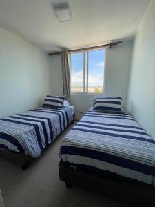 two beds in a room with a window at Depto 941 in La Serena