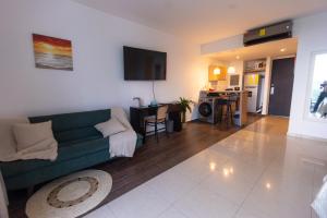 a living room with a green couch and a kitchen at Relax Loft on the beach Town Center Playa B in Río Hato