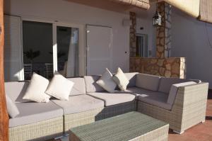 a wicker couch with pillows on a patio at Villa Mónica by Mirador de Sotavento Apartments in Cardón