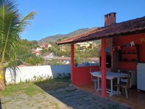 a small red house with a table on the patio at Casa Campobello - centro de Miguel Pereira in Miguel Pereira