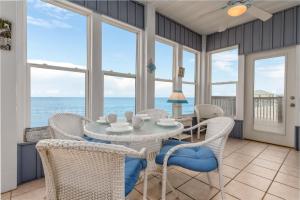 ein Esszimmer mit Tisch und Stühlen und dem Meer in der Unterkunft Blue Haven in Dauphin Island