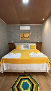 a bedroom with a large bed with a yellow blanket at POUSADA IRMAOS ATINS in Atins