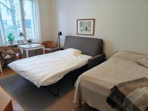 een slaapkamer met twee bedden, een tafel en een raam bij Eskolampi in Helsinki