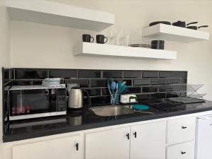 a kitchen with a microwave and a black tile wall at Lemongrass Condos in Gros Islet +2 photos
