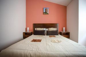 a bedroom with a large bed with an orange wall at Casa do Avô in Sortelha