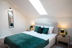 a white bedroom with a bed with a green blanket at Zenith - Alpine Retreat in Zărneşti