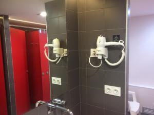 a bathroom with a shower with a mirror and red stalls at Hostel Casa Ibarrola in Pamplona