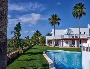 a house with a swimming pool and palm trees at Villa Cas Hespero in San Antonio
