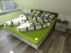 - une chambre avec un lit vert et des oreillers dans l'établissement Groß Kölzig - Moderne Ferienwohnung in ländlicher Idylle, à Neiße-Malxetal
