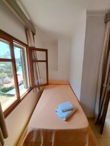 a small room with a bed with a window at Hostal Playa in Cala Santanyi