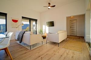 a living room with white furniture and a ceiling fan at Sunset Hills Transylvania in Odorheiu Secuiesc