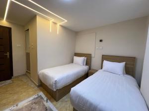 two beds in a small room with white sheets at Isis Pyramids View Inn in Cairo