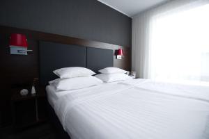 een groot bed met witte lakens en kussens in een slaapkamer bij Best Western Plus Plaza Hotel Graz in Graz +37 foto's
