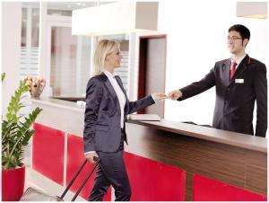 a man and a woman shaking hands at a counter at Best Western Plus Amedia Wien in Vienna
