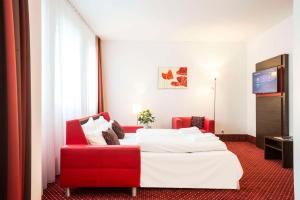 a hotel room with a bed and a red chair at Best Western Plus Amedia Wien in Vienna