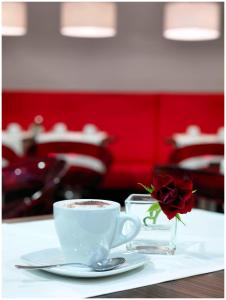a cup of coffee sitting on a table with a rose at Best Western Plus Amedia Wien in Vienna