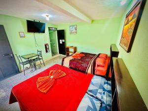 a bedroom with two beds and a table and a television at Hotel Emiss Panajachel in Panajachel +30 photos