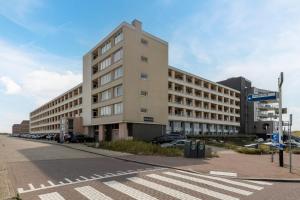 a large building with cars parked in a parking lot at Lovina Beach House by Urban Home Stay in Egmond aan Zee