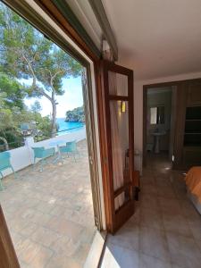an open door to a patio with a view of the ocean at Hostal Playa in Cala Santanyi