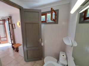 a bathroom with a toilet and a door at Hostal Playa in Cala Santanyi