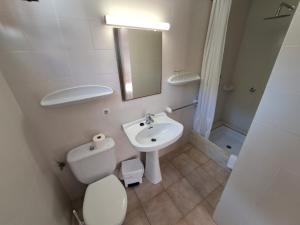 a white bathroom with a toilet and a sink at Hostal Playa in Cala Santanyi