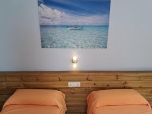 two beds in a room with a boat in the water at Hostal Playa in Cala Santanyi