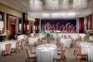 a banquet hall with white tables and chairs and chandeliers at Ajman Saray, a Luxury Collection Resort, Ajman in Ajman  +37 photos