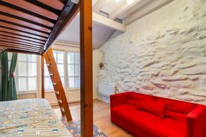 a red couch in a room with a stone wall at La petite maison d 'Ascou in Ascou