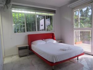 a red bed in a white room with windows at Casa Campestre Bello Atardecer Cerca al Parque del Café con Piscina in La Esmeralda