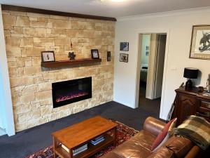 Una sala de estar con una pared de piedra con chimenea. en Ski, Mtn Bike or Hike from the heart of Thredbo, en Thredbo
