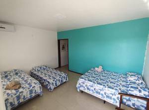 Una habitación con dos camas y una pared azul. en Vanessa pousada familiar, en São Gabriel