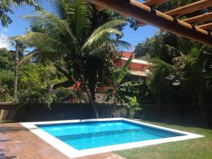 a swimming pool in front of a house with a palm tree at D'ajuda Flat in Arraial d'Ajuda