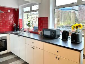 a kitchen with a counter with a microwave and a television at 3 Twin Bedroom Entire House Sleeps 10 Driveway Parking near Coventry University and City Center in Coventry +31 photos