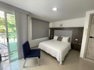 a bedroom with a bed and a blue chair at Hotel Juan Pablo 2 in Ríohacha