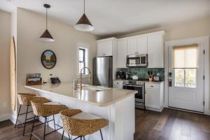 a kitchen with white cabinets and a counter with bar stools at The Hen Houses in Wildwood
